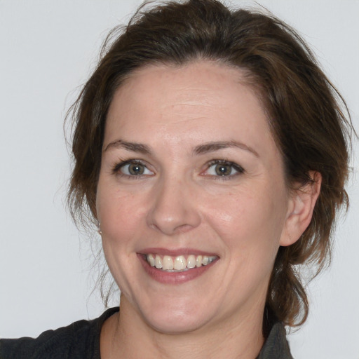 Joyful white adult female with medium  brown hair and grey eyes