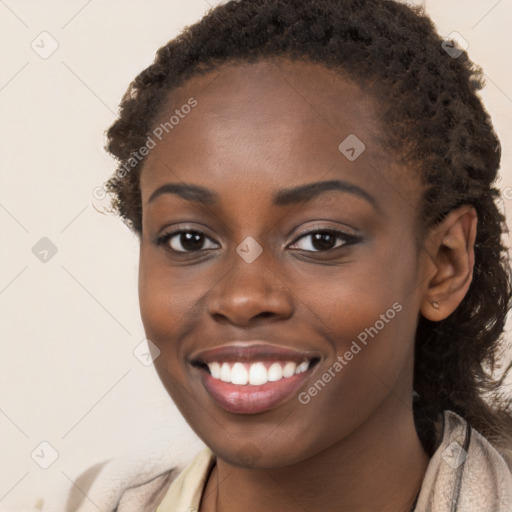 Joyful black young-adult female with long  brown hair and brown eyes