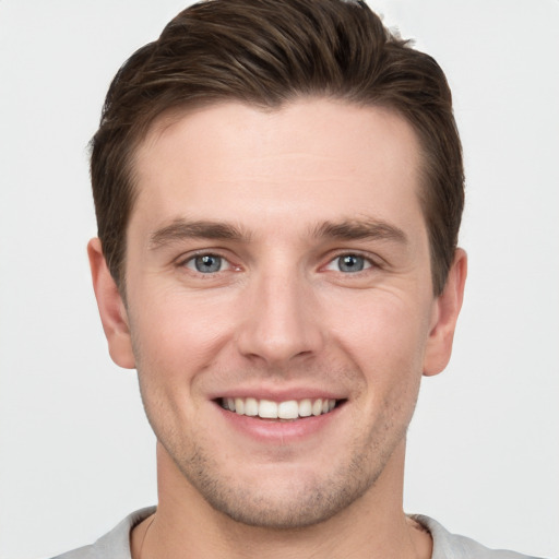 Joyful white young-adult male with short  brown hair and grey eyes