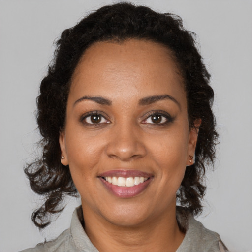 Joyful black young-adult female with long  brown hair and brown eyes