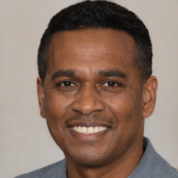 Joyful black adult male with short  black hair and brown eyes