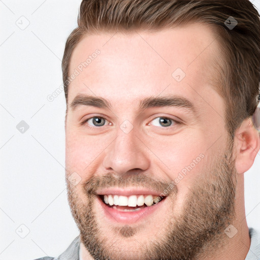 Joyful white young-adult male with short  brown hair and grey eyes