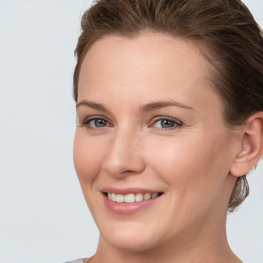 Joyful white young-adult female with medium  brown hair and grey eyes