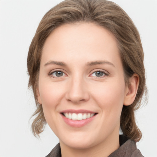 Joyful white young-adult female with medium  brown hair and grey eyes