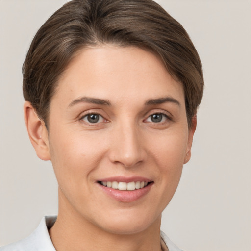 Joyful white young-adult female with short  brown hair and grey eyes