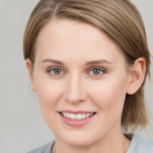 Joyful white young-adult female with medium  brown hair and grey eyes