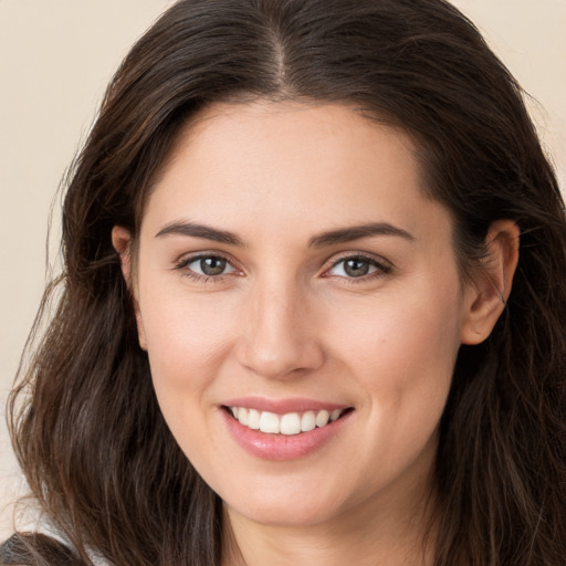 Joyful white young-adult female with long  brown hair and brown eyes