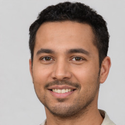 Joyful white young-adult male with short  black hair and brown eyes