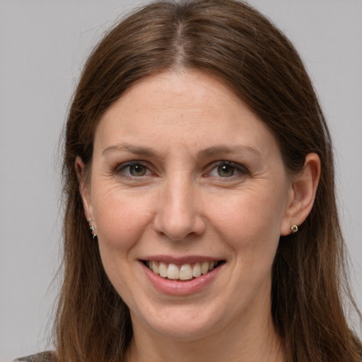 Joyful white adult female with long  brown hair and grey eyes