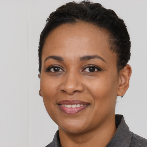 Joyful black young-adult female with short  black hair and brown eyes