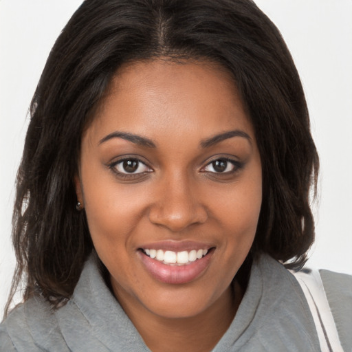 Joyful black young-adult female with long  brown hair and brown eyes