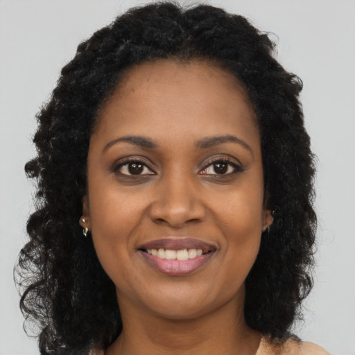 Joyful black young-adult female with long  brown hair and brown eyes