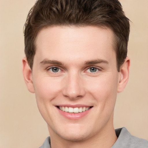 Joyful white young-adult male with short  brown hair and grey eyes