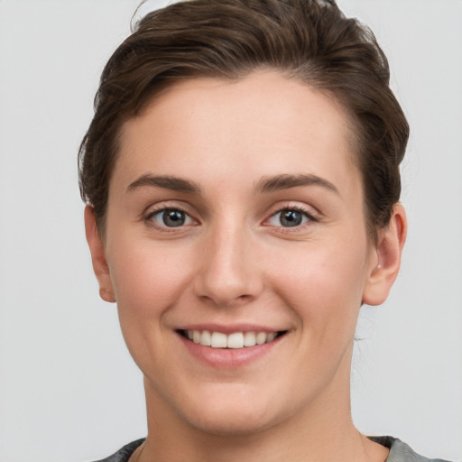 Joyful white young-adult female with short  brown hair and grey eyes