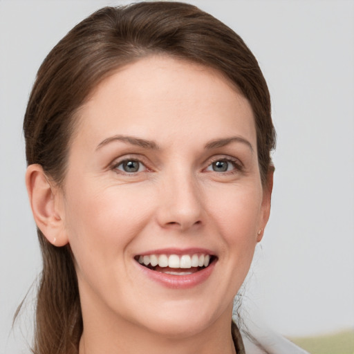 Joyful white young-adult female with medium  brown hair and grey eyes