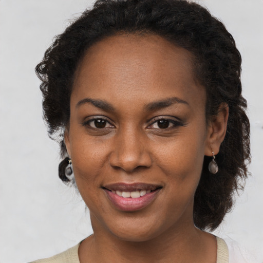 Joyful black young-adult female with long  brown hair and brown eyes