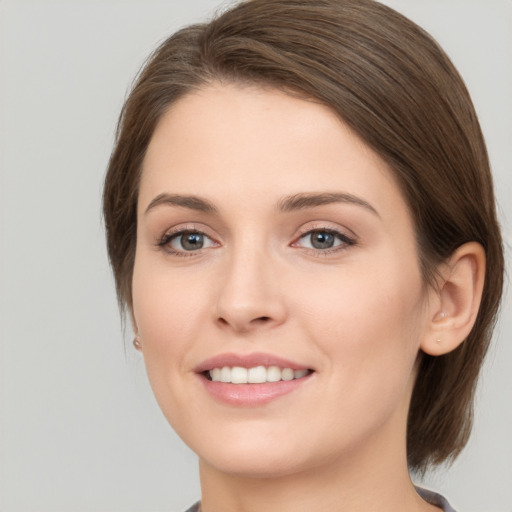 Joyful white young-adult female with medium  brown hair and grey eyes