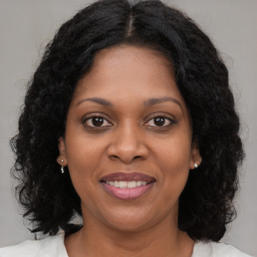 Joyful black young-adult female with long  brown hair and brown eyes