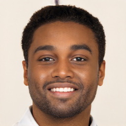 Joyful black young-adult male with short  black hair and brown eyes
