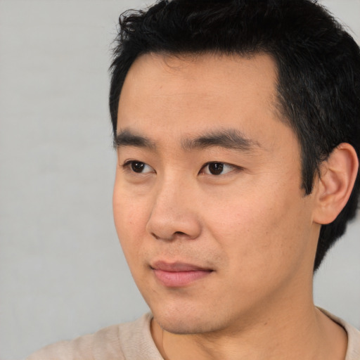 Joyful asian young-adult male with short  black hair and brown eyes