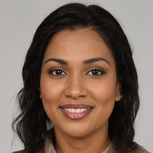 Joyful black young-adult female with long  brown hair and brown eyes