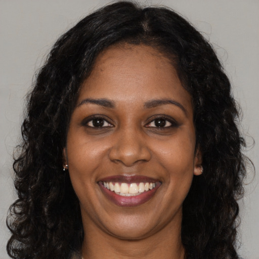 Joyful black young-adult female with long  black hair and brown eyes