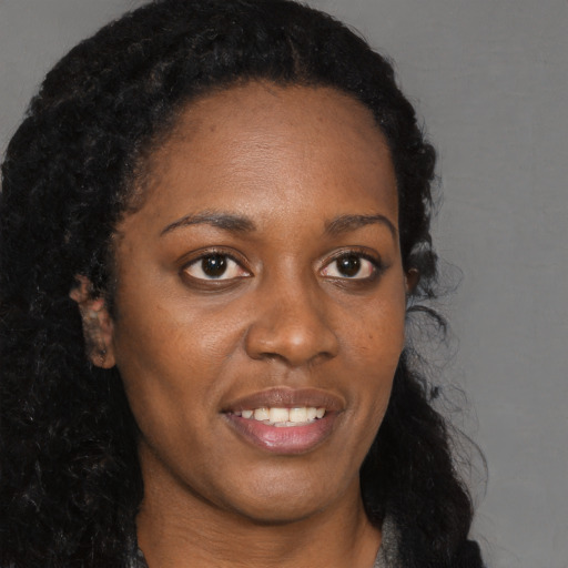Joyful black young-adult female with long  brown hair and brown eyes