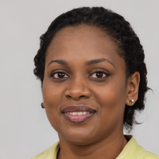 Joyful black young-adult female with short  black hair and brown eyes