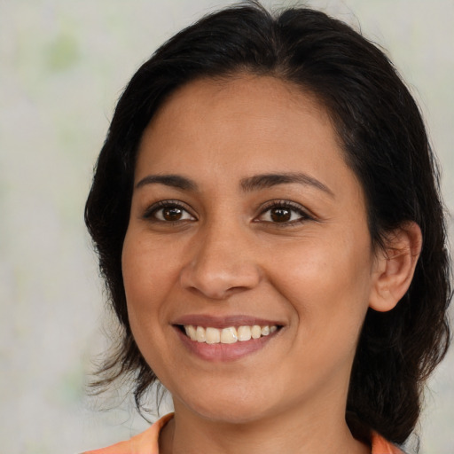 Joyful latino young-adult female with medium  brown hair and brown eyes