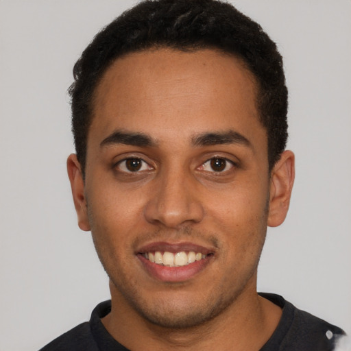 Joyful black young-adult male with short  brown hair and brown eyes