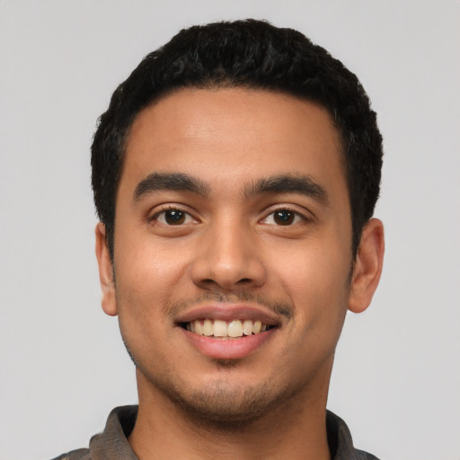 Joyful latino young-adult male with short  black hair and brown eyes