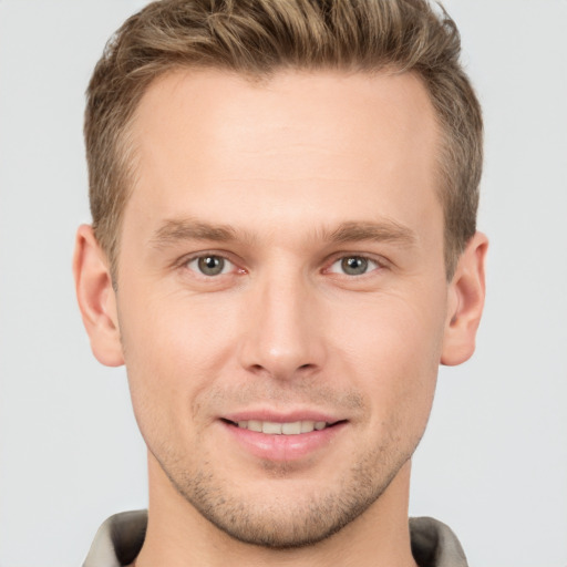 Joyful white young-adult male with short  brown hair and grey eyes