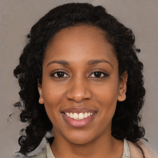 Joyful black young-adult female with long  black hair and brown eyes
