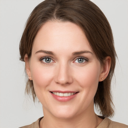 Joyful white young-adult female with medium  brown hair and grey eyes