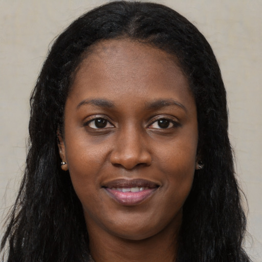 Joyful black young-adult female with long  black hair and brown eyes