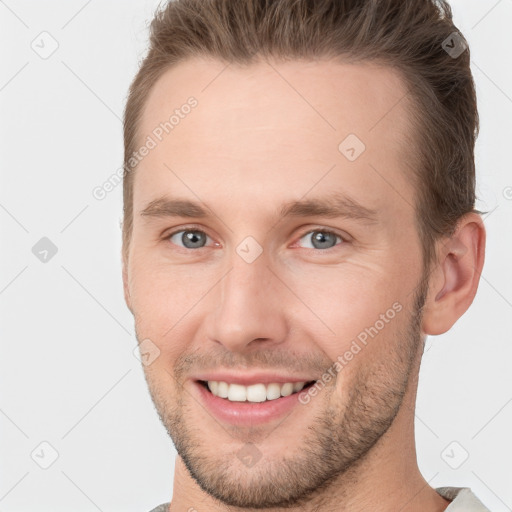 Joyful white young-adult male with short  brown hair and grey eyes