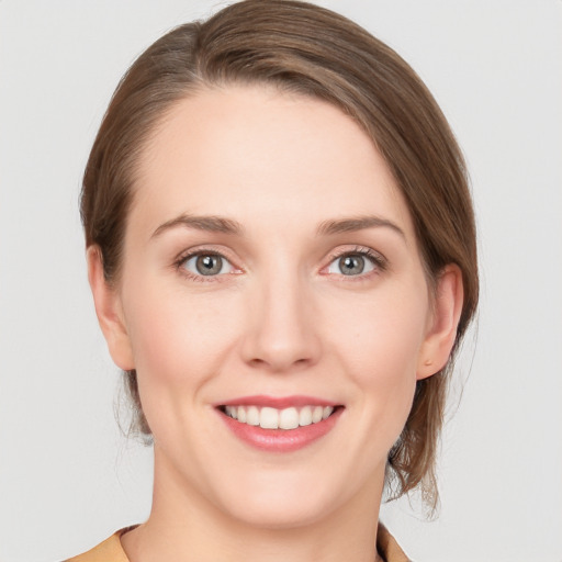 Joyful white young-adult female with medium  brown hair and grey eyes