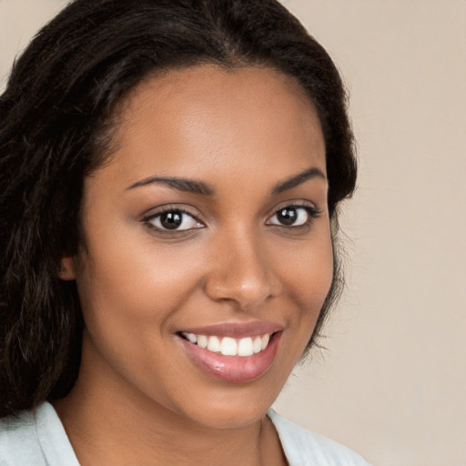 Joyful black young-adult female with long  brown hair and brown eyes