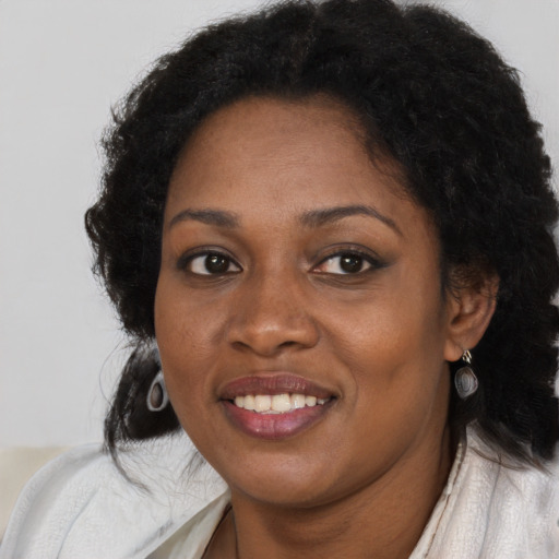Joyful black young-adult female with long  brown hair and brown eyes