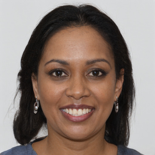 Joyful black young-adult female with long  brown hair and brown eyes