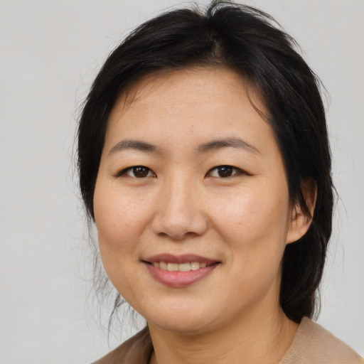Joyful asian adult female with medium  brown hair and brown eyes