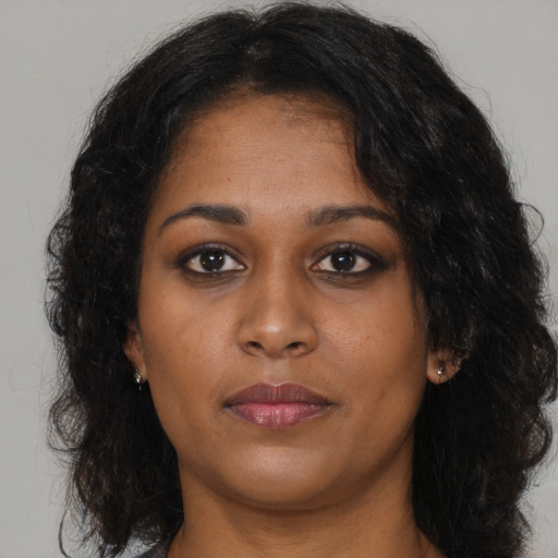 Joyful black young-adult female with long  brown hair and brown eyes