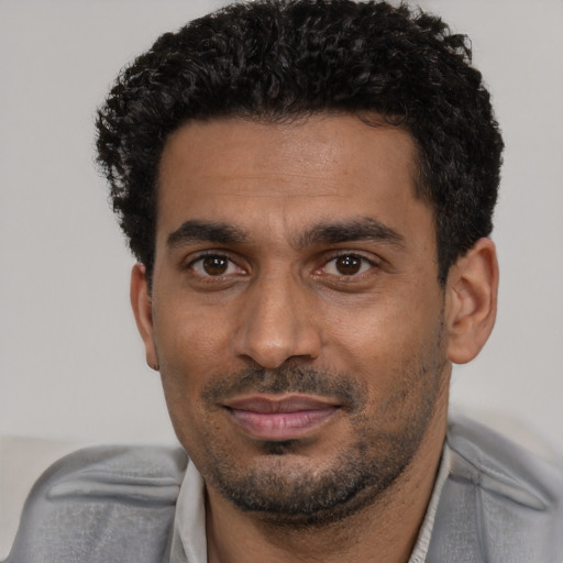 Joyful black adult male with short  black hair and brown eyes
