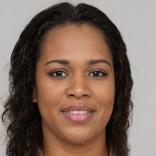 Joyful black young-adult female with long  brown hair and brown eyes