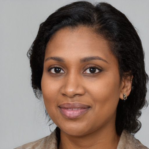 Joyful black young-adult female with long  brown hair and brown eyes