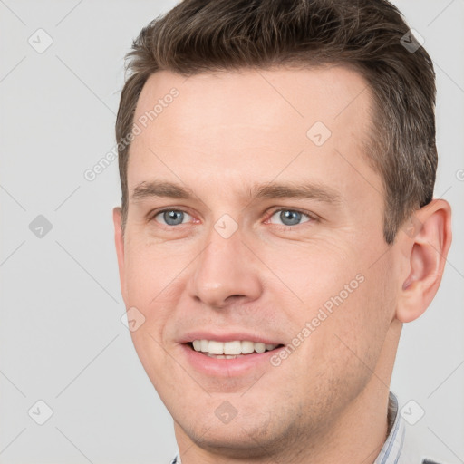 Joyful white young-adult male with short  brown hair and grey eyes