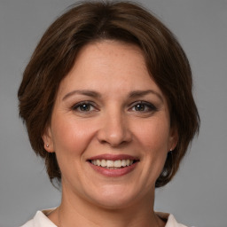 Joyful white adult female with medium  brown hair and grey eyes