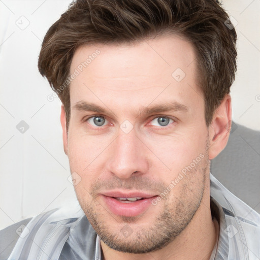 Joyful white young-adult male with short  brown hair and grey eyes