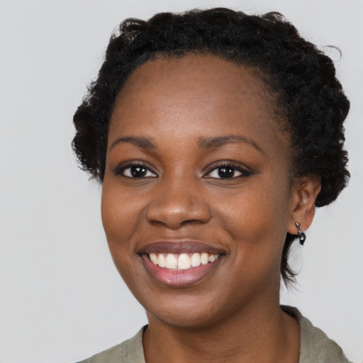 Joyful black young-adult female with short  black hair and brown eyes