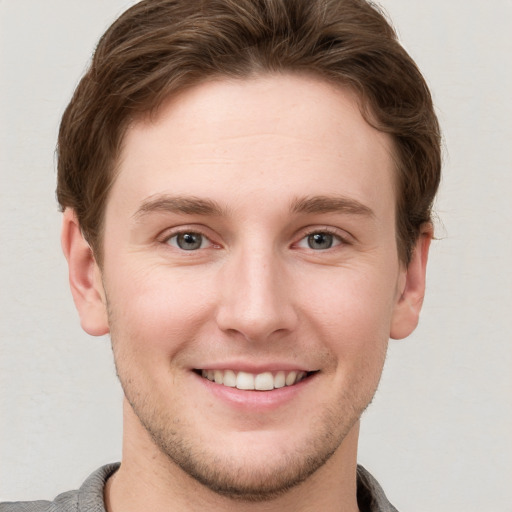 Joyful white young-adult male with short  brown hair and grey eyes